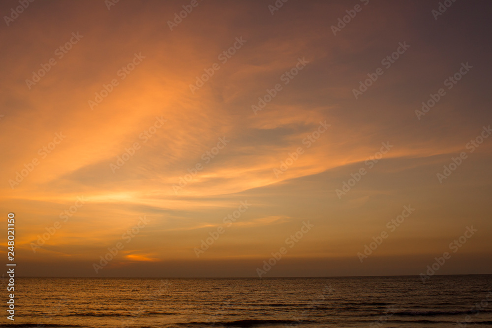 yellow clouds in the blue purple pink sunset sky against the sea