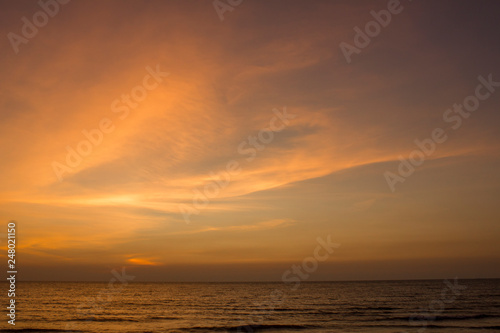 yellow clouds in the blue purple pink sunset sky against the sea © Pavel