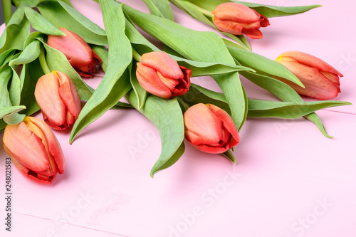 Bouquet of red tulips on pink painted wood background, side view, with space for text, for Valentine's Day or Mother's Day