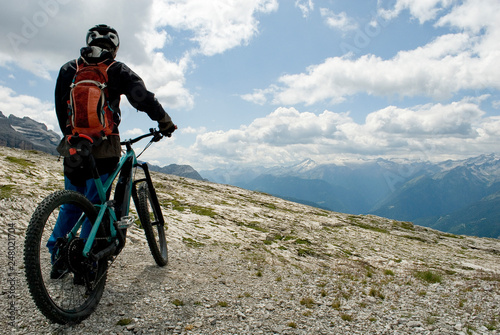 man with an electric bike, e-bike, ebike, mtb, observes Brenta Dolomites mountains, unesco heritage, Madonna di Campiglio, summer, sport, adventure, travel, Alps, Trentino, Alto Adige, Italy