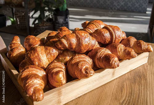 Wooden tray filled with freshly baked tasty golden butter croissants