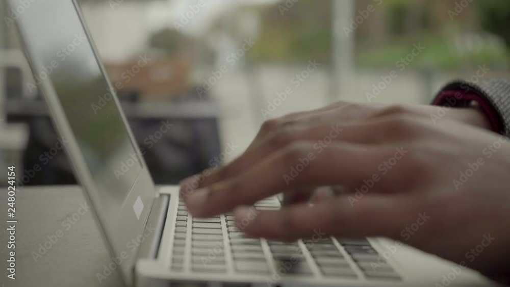 Cropped shot of man working with laptop computer. Close-up partial view of African American man typing on laptop computer at outdoor cafe. Freelance concept Cropped shot of man working with laptop computer. Close-up partial view of African American man typing on laptop computer at outdoor cafe. Freelance concept