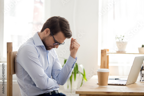 Obraz na plátně Frustrated man feeling loser sitting near laptop shocked by bankruptcy