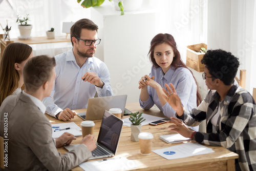 Colleagues listening to african employee telling opinion at group meeting photo