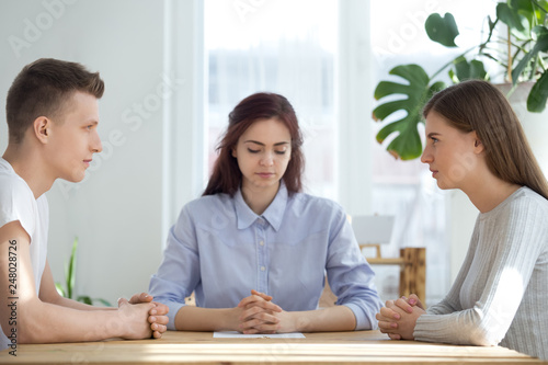 Unhappy married couple sitting opposite getting divorced in lawyer office