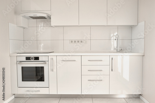 White modern kitchen in contemporary flat. Interior design of white modern kitchen. Minimalism in style.