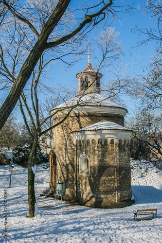 Prague  Czech Republic   Europe - February 5 2019  Medieval rotunda of saint Martin built in 11th century made of stone standing at Vysehrad  snow on ground  trees  sunny day  blue sky  vertical image