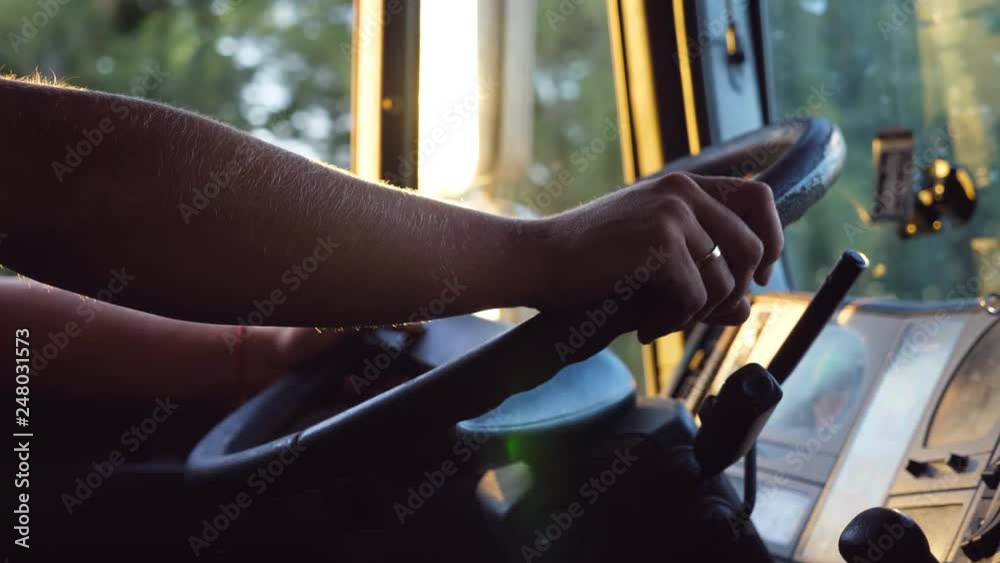 Unrecognizable man holding his hands on steering wheel and driving car at country road on warm summer day. Truck driver rides to destination. View from the lorry cab. Slow motion Close up