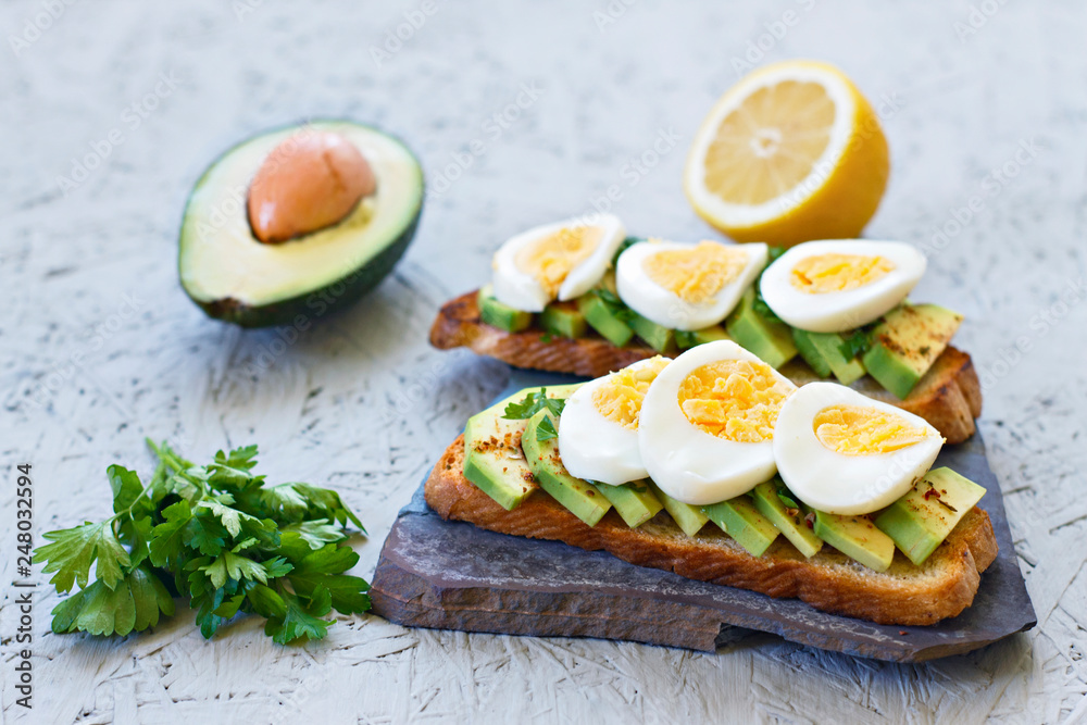 The concept of proper nutrition. Toasts with avocado, lemon, chilli or paprika and eggs on a gray background The concept of proper nutrition. Toasts with avocado, lemon, chilli or paprika and eggs on a gray background