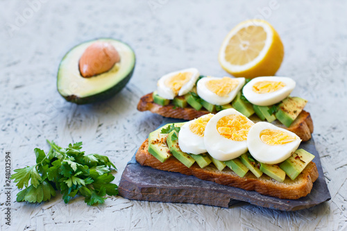 The concept of proper nutrition. Toasts with avocado, lemon, chilli or paprika and eggs on a gray background
