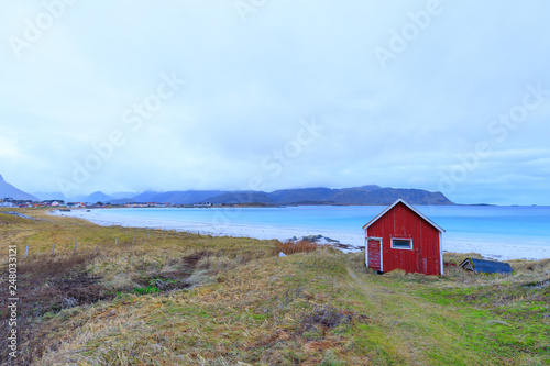 Blue water at beach Rambergstranda with typical red fisher hut in Ramberg, Norway