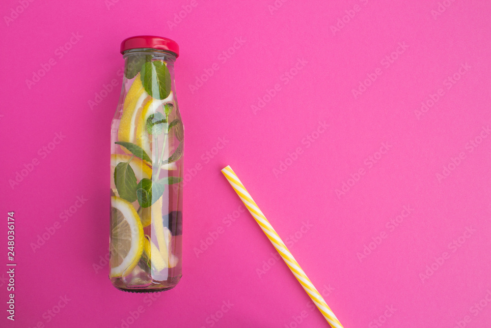Detox water with lemon and mint in the glass bottle  on the pink  background.Top view.Copy space.
