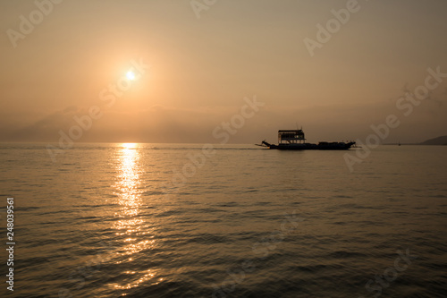 Ferry boat on the  Ocean  silhouetted against a setting sun and orange sky. Silhouette of the Ferry ship over the sunset Ferry float in the sea in the evening. International transportation, shipping,  © kanpisut