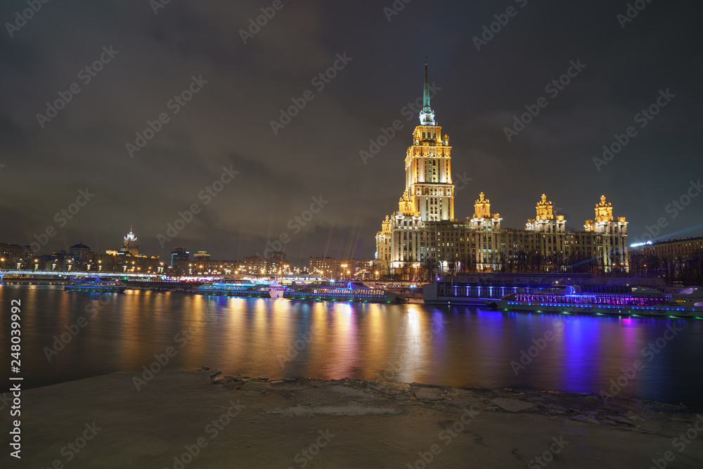 Fototapeta premium Hotel Ukraine (Radisson Royal Hotel) in bright lights and Moskva river in night winter reflections of the night Moscow.