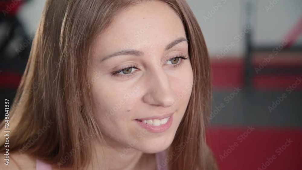 Beautiful athletic young girl resting after classes in the gym and drinking water from a bottle. Beautiful athletic young girl resting after classes in the gym and drinking water from a bottle.