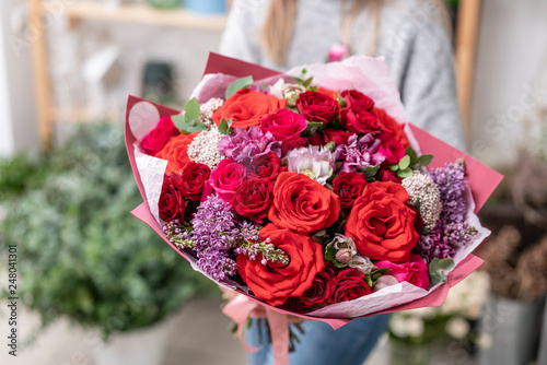 beautiful fresh cut bouquet of mixed flowers in woman hand. the work of the florist at a flower shop. Red color