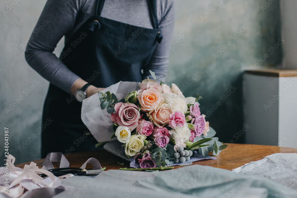 Девушка флорист собирает красивый букет girl florist makes a beautiful bouquet - obrazy, fototapety, plakaty 
