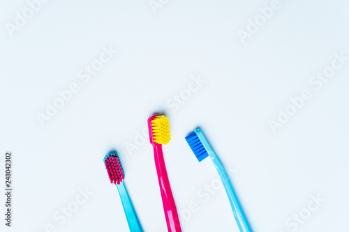 Colorful tooth brushes with bright color bristles on a light pastel blue background. Dental tools with empty space for text for your mockup.