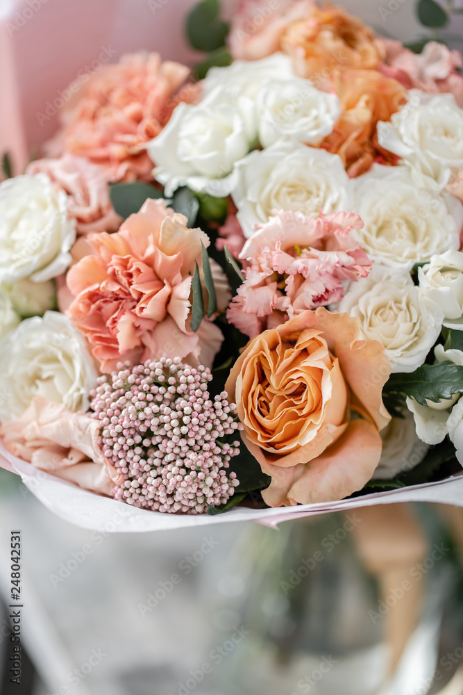 Obraz premium beautiful fresh cut bouquet of mixed flowers in vase on wooden table. The work of the florist at a flower shop. Delicate Pastel tones color