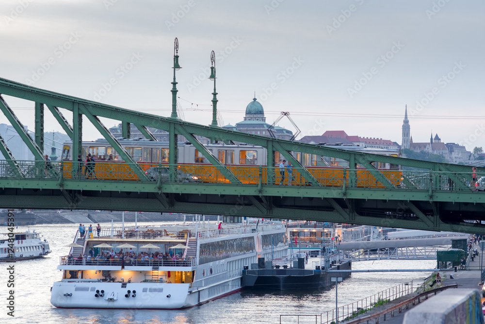 Tram moving on a bridge, cruise ship at berth, old city skyline