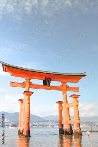 Little girl at the Itsukushima shrine great orange gate O-torii at the Miyajima island in Japan photo