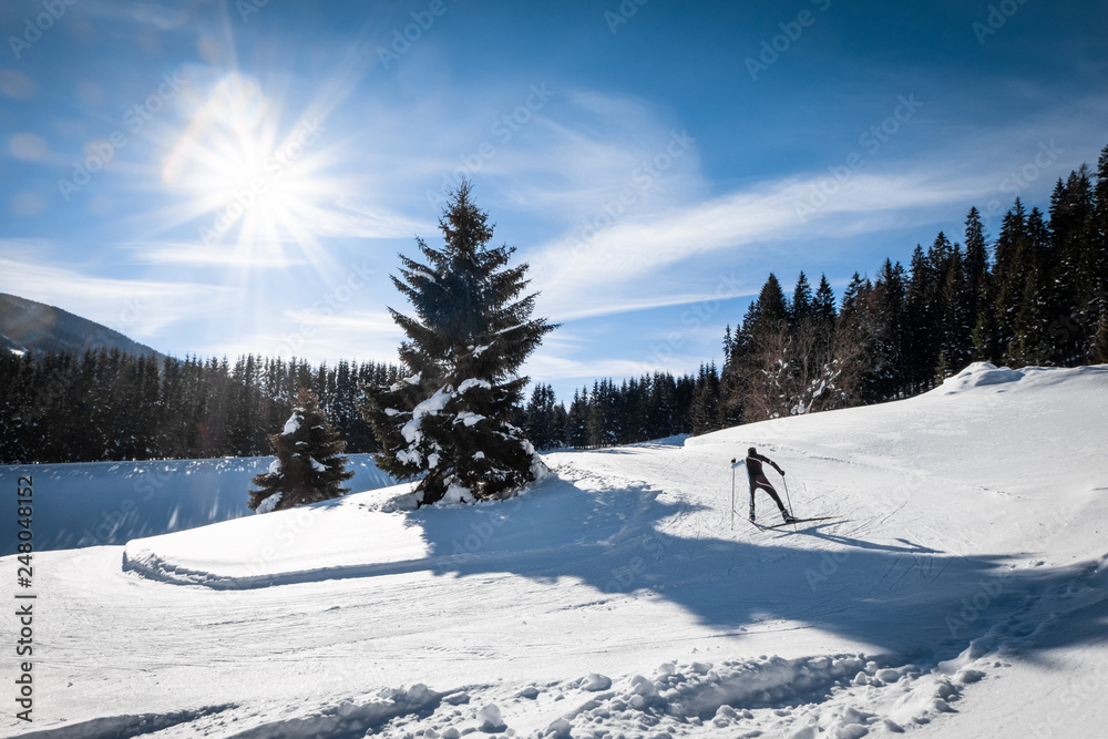 Adult man running cross-country skiing in snow-covered holiday resort Hohentauern