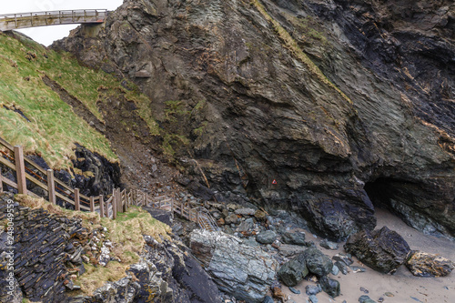 a ravine between the mountains that go to the sea; the wooden staircase with wooden fence leads down from the rocks to the water that has retreated during low tide