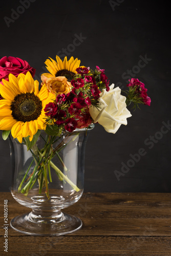 Bouquet of white yellow and red flowers in a vase on a dark background