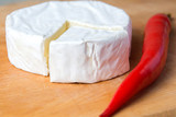 white brie cheese on the kitchen board with red chot chili paper