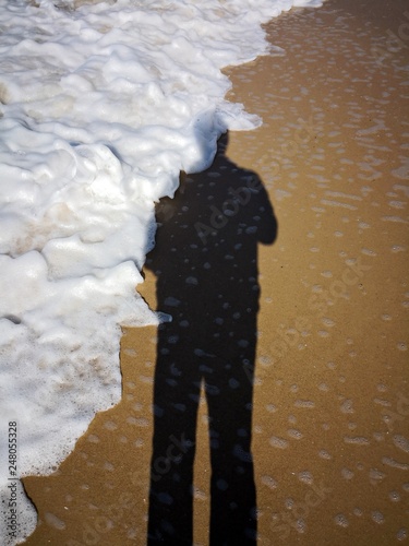 Shadow of a man on the sand at the seaside. Wave cover the shadow