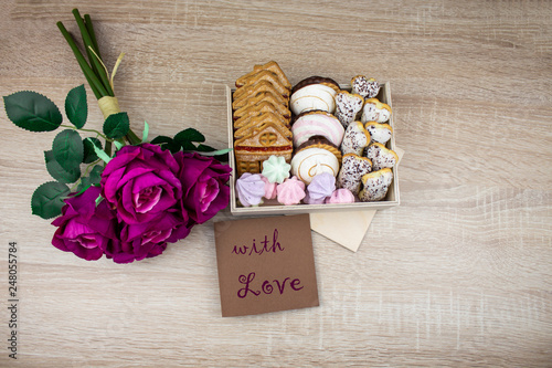 Chocolate cookies on a wooden table. A variety of cookies in a box with flowers and a card. Assorted cookies. copy space photo