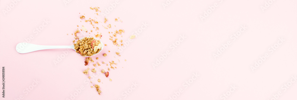 Granola Cereal bar with Strawberrie in a white spoon on a pink background..Breakfast. Healthy Food sweet dessert snack. Diet Nutrition Concept.Vegetarian food. Flat Lay.Top View. Copy space