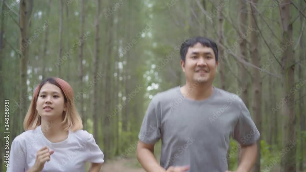 Healthy young athletic sporty Asian runner man and woman in sports clothing running and jogging on forest trail. Lifestyle fit and active women exercise in the forest concept.