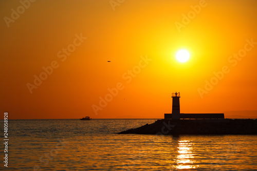 breakwater and lighthouse in the aegean sea, Turkey. reverse light in the sunset © kakafonik
