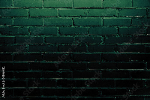 Dark green brick wall illuminated at the top. Grunge background with space for text or image. Empty template and mockup for designers.