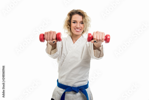 Portrait of female wearing martial arts costume training with dumbbells