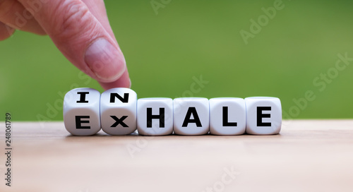 Inhale,Exhale concept. Hand turns dice and changes the word 