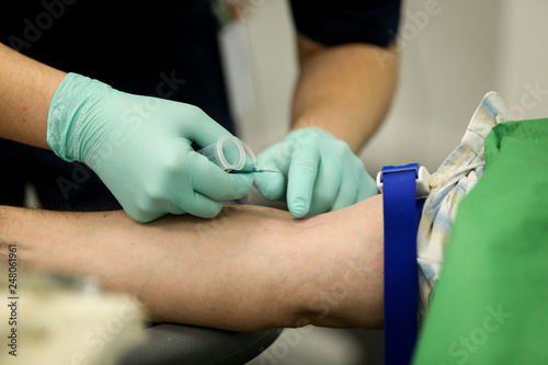 Details with the hands of a doctor preparing to take blood from the vein of a patient with a catheter