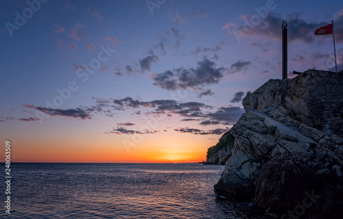 Obelisk and flag on the cliffs at dusk photo
