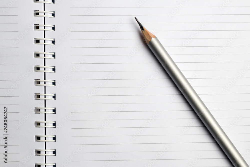 Education concept. White notebook with silver pencil Education concept. White notebook with silver pencil