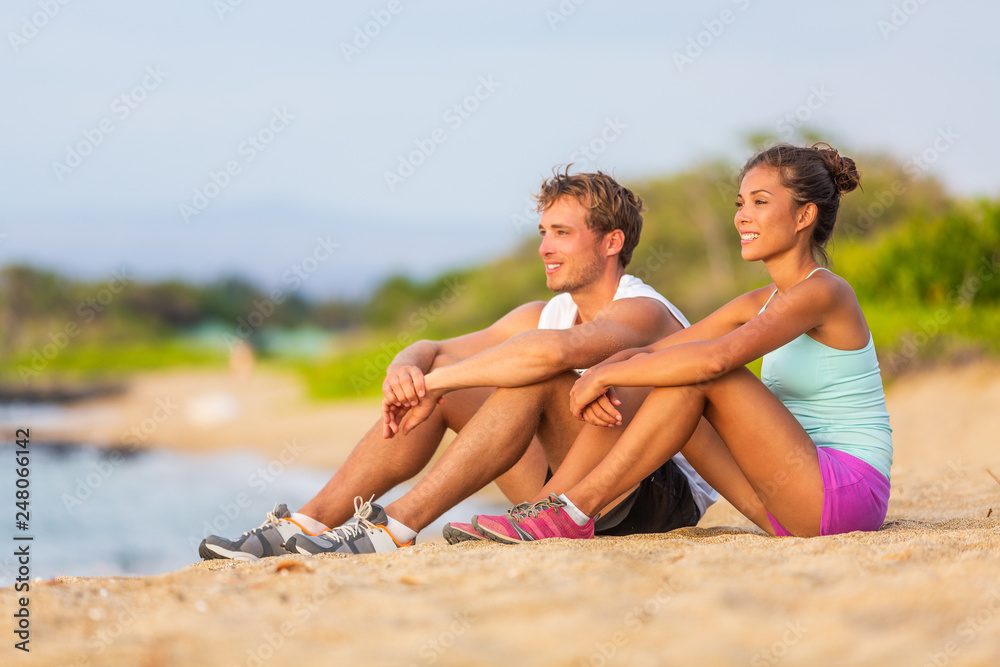 Fit people enjoying sunset on beach after workout training. Fitness active couple woman and man on holiday. Travel beach vacation. Fit people enjoying sunset on beach after workout training. Fitness active couple woman and man on holiday. Travel beach vacation.