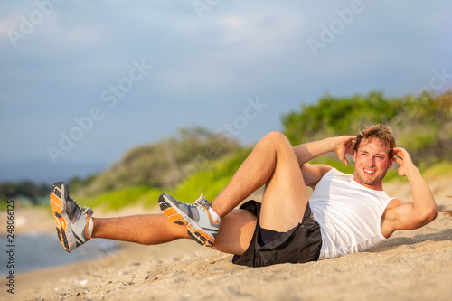 Exercise sit up fitness man doing situps outside in summer beach. Fit athlete working out cross training bicycle crunches to activate obliques mucles abs workout. Caucasian muscular sports model. photo