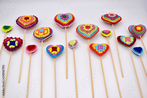 Knitted hearts on wooden sticks on a white background. Valentine's Day, handmade.