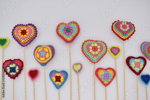 Knitted hearts on wooden sticks on a white background. Valentine's Day, handmade.