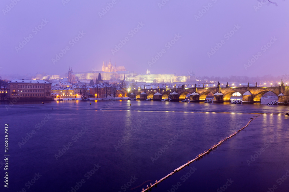 Obraz premium Foggy night Prague Lesser Town with gothic Castle, Bridge Tower and St. Nicholas' Cathedral in the Snowstorm, Czech republic
