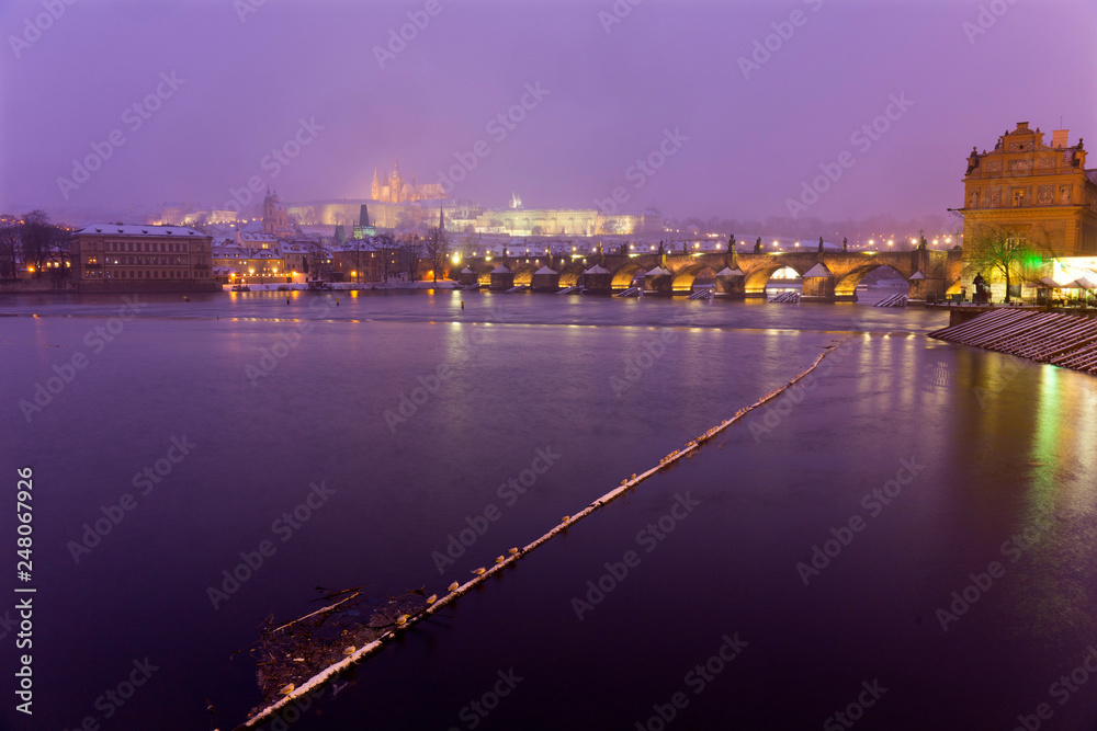 Obraz premium Foggy night Prague Lesser Town with gothic Castle, Bridge Tower and St. Nicholas' Cathedral in the Snowstorm, Czech republic
