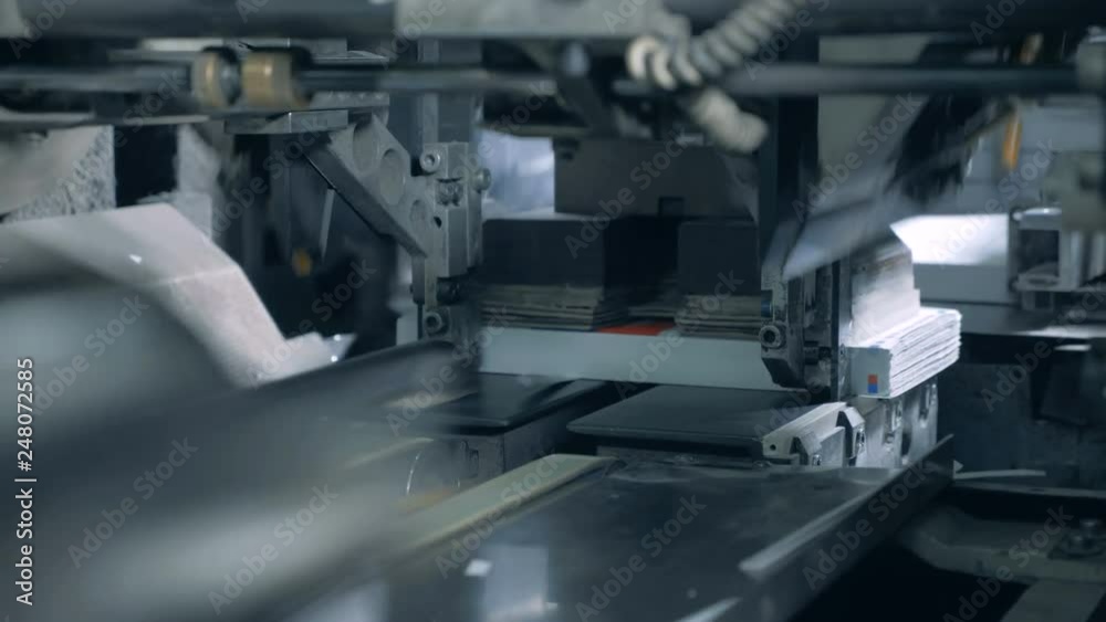 One machine moves books on a printing conveyor, close up. One machine moves books on a printing conveyor, close up.