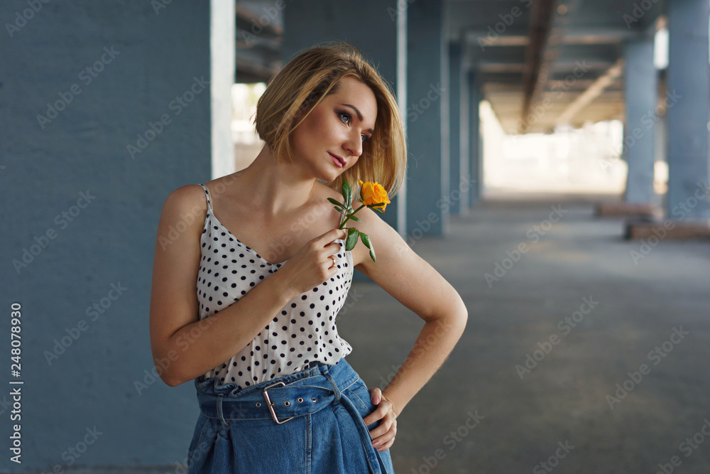 Young attractive girl holding yellow rose flower in her hands. Spring romantic mood. She is dreamily looking sideways. Young attractive girl holding yellow rose flower in her hands. Spring romantic mood. She is dreamily looking sideways.