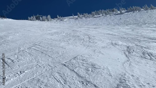 Skier on steep white snow and blue sky