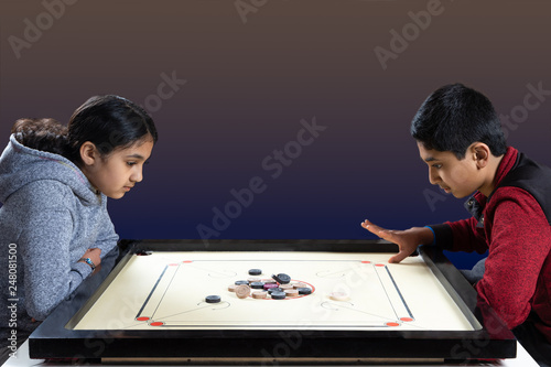 Indian Siblings Playing Carrom on the Carrom Board